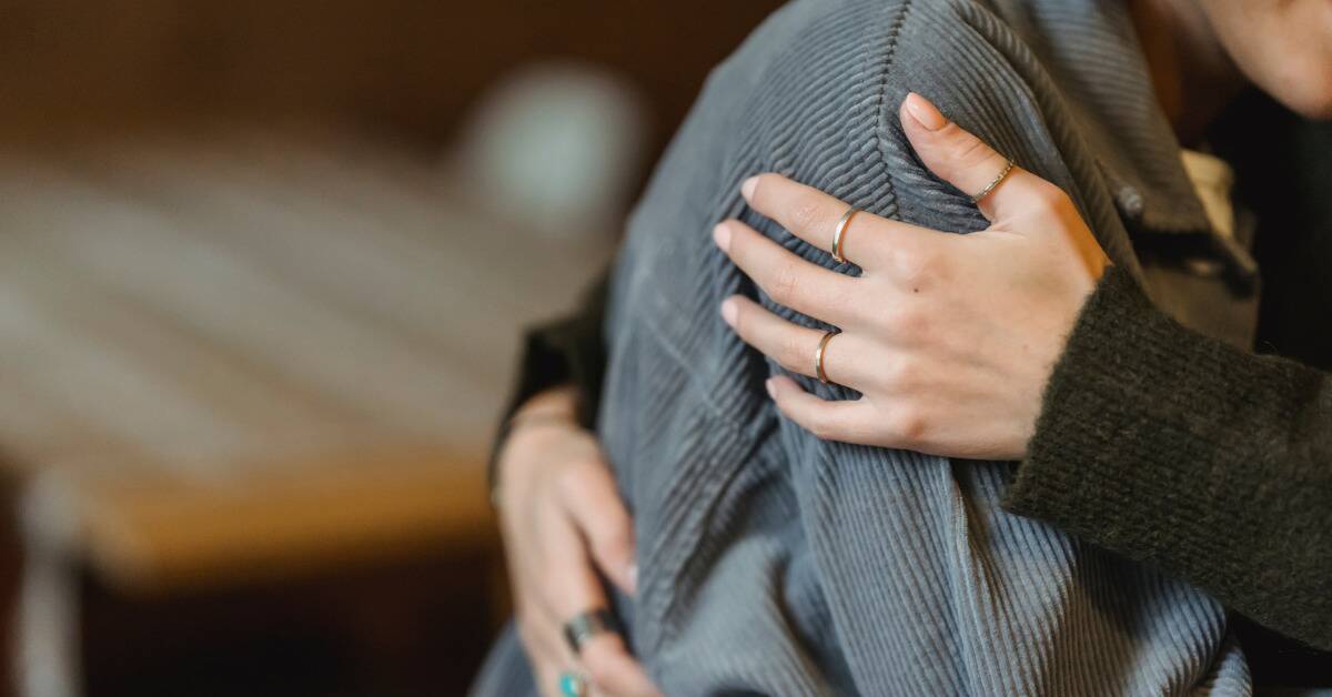 A close shot of two people hugging, only their arms and hands visible.