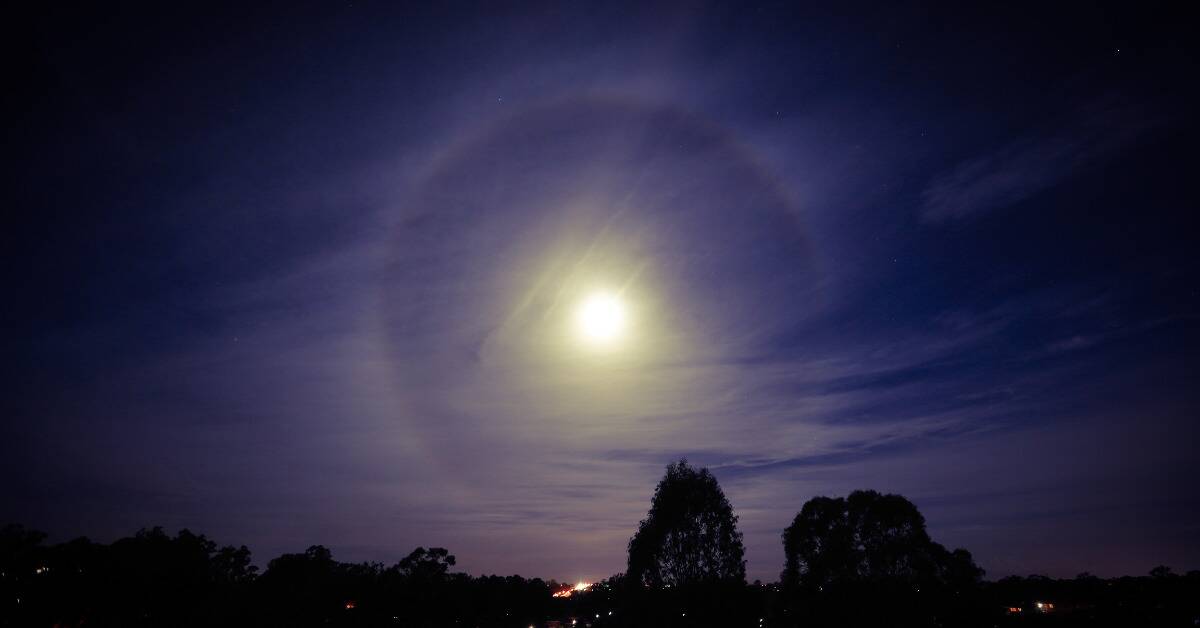 A lunar halo with a yellow tinge over a purple sky.