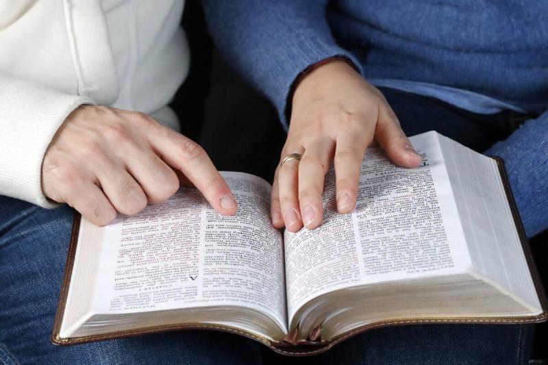 Man and woman reading together the bible at home