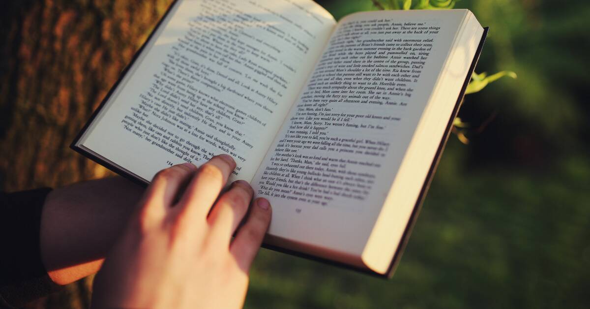 Someone reading outside, holding the book open.