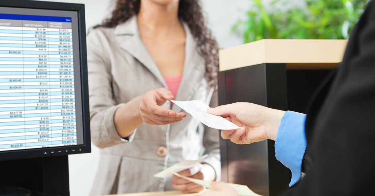 A woman being handed a check by a bank teller.