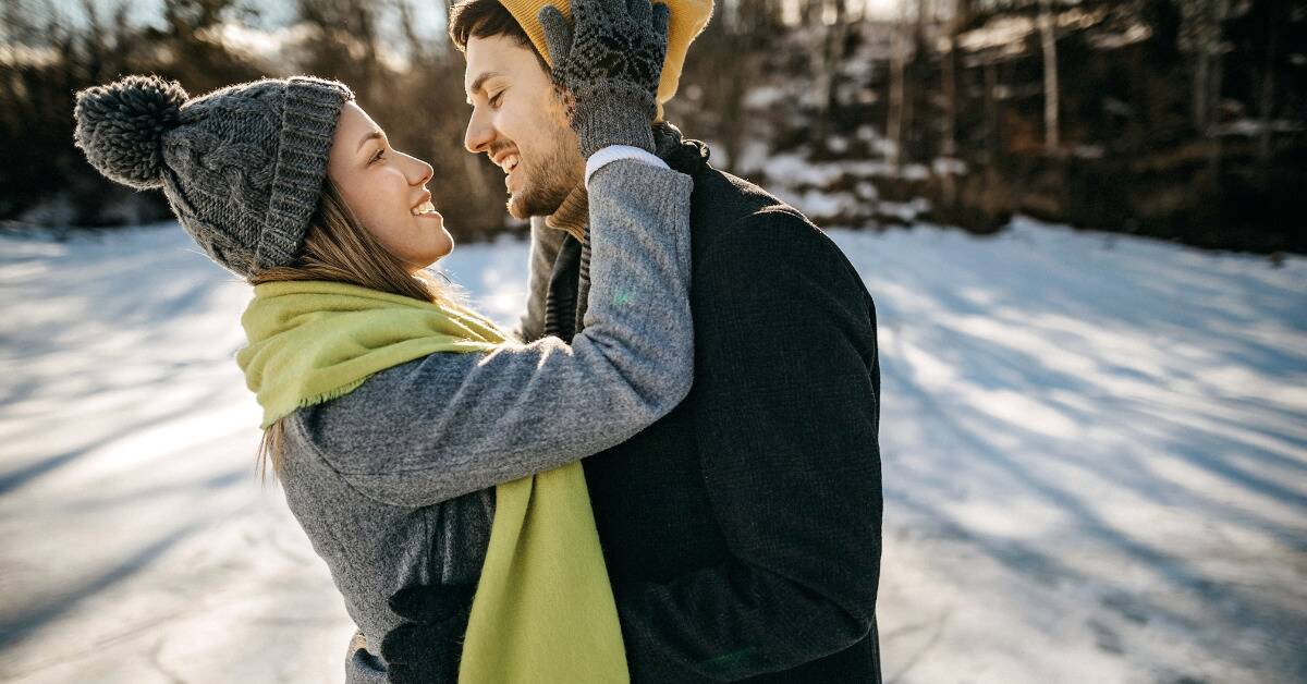 A couple embracing one another while standing outside in the snow.