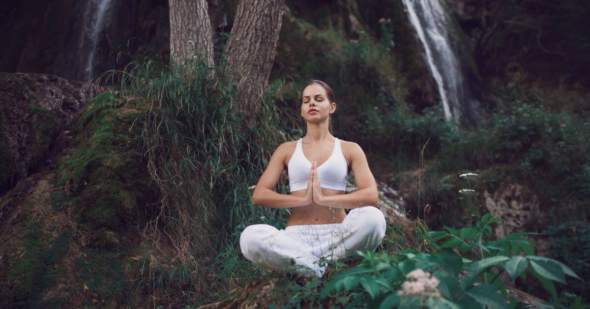 A woman meditating in a forest.