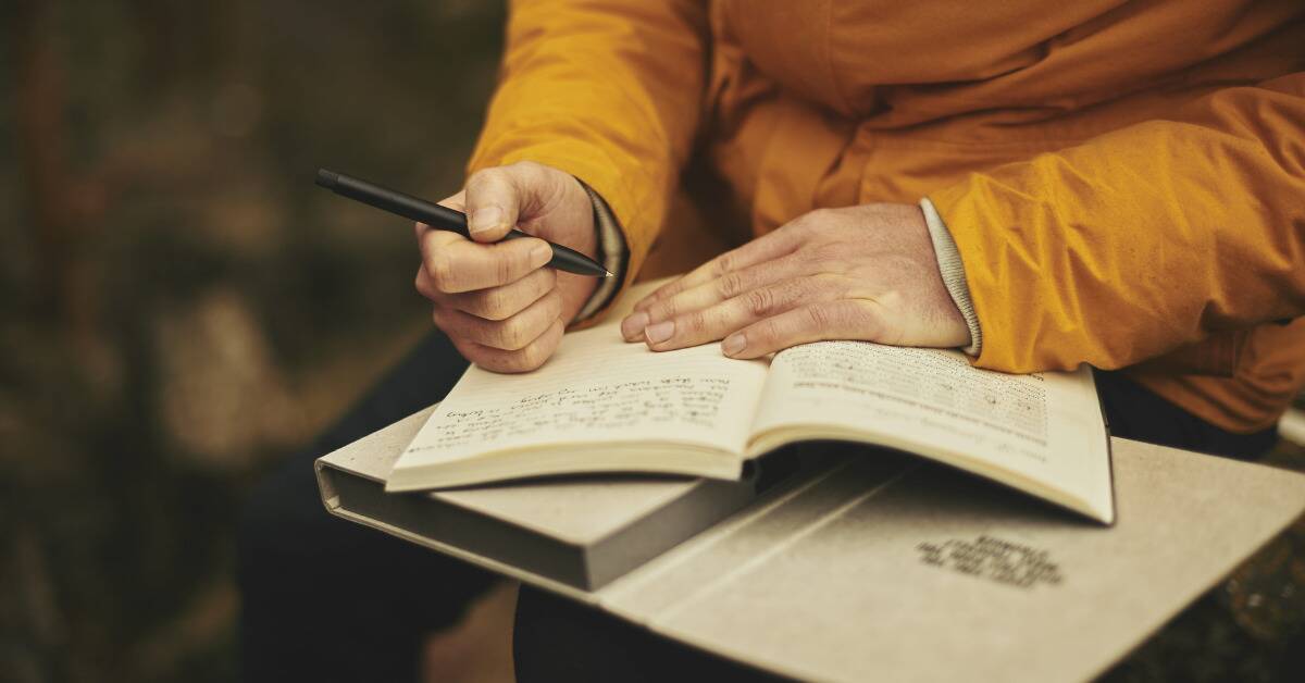 Someone sitting outside to write in a journal.