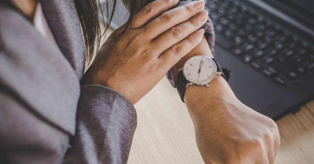 A woman pushing she sleeve up to check her watch. 