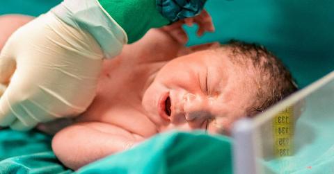 A nurse moving the clip a newborn baby's umbillical cord.