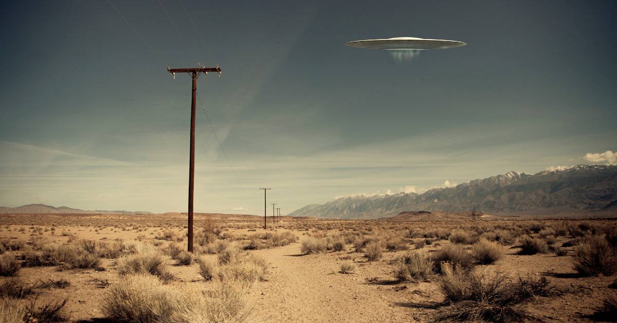 An edited photo of a saucer UFO hovering above a desert landscape.