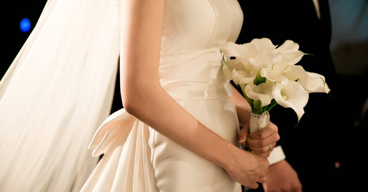 A closeup of a bride holding her bouquet as she walks down the aisle.