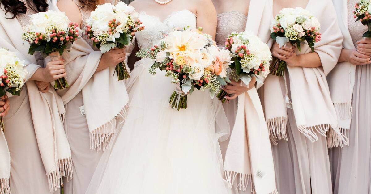 A bride standing with all her bridesmaids, all holding bouquets.