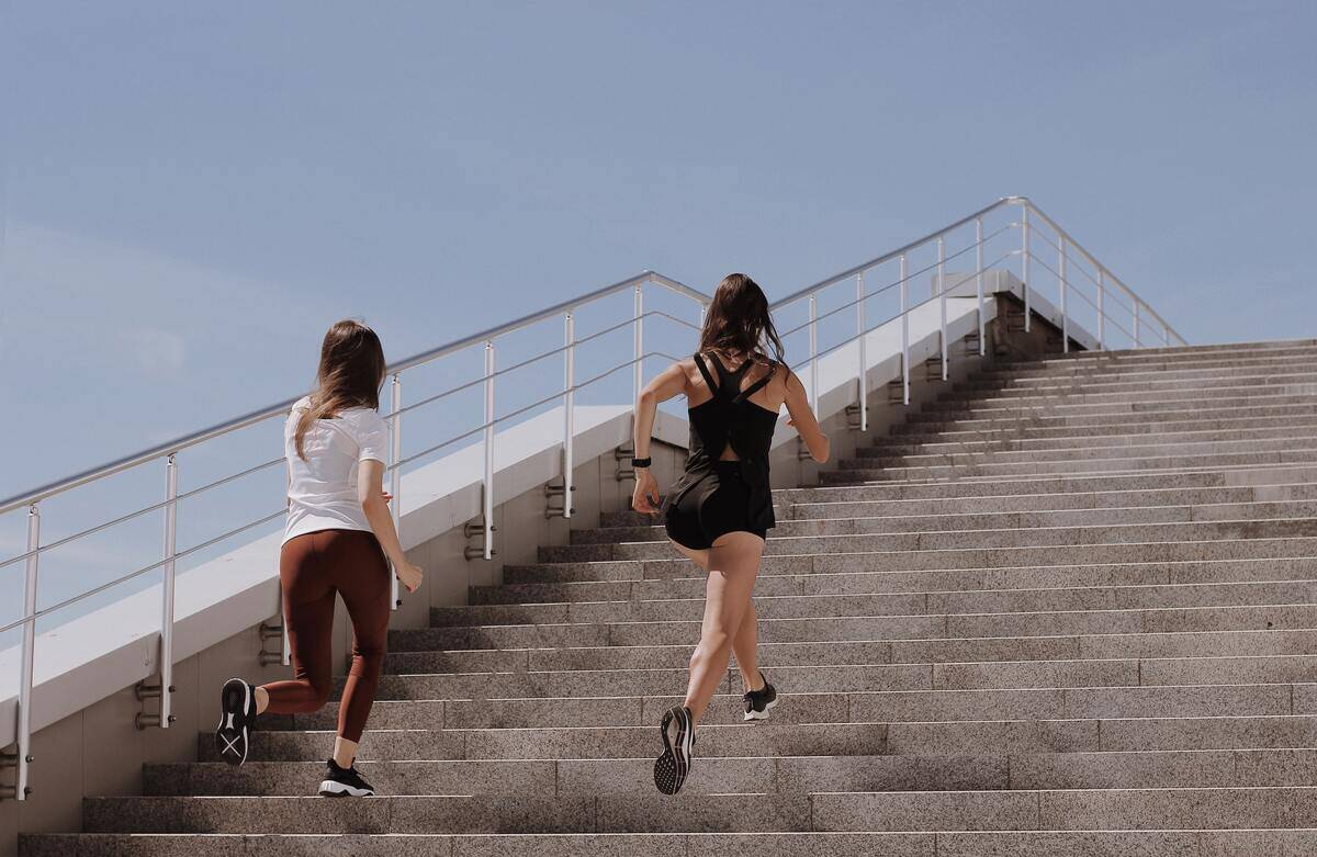 Two women in workout gear jogging up the stairs.