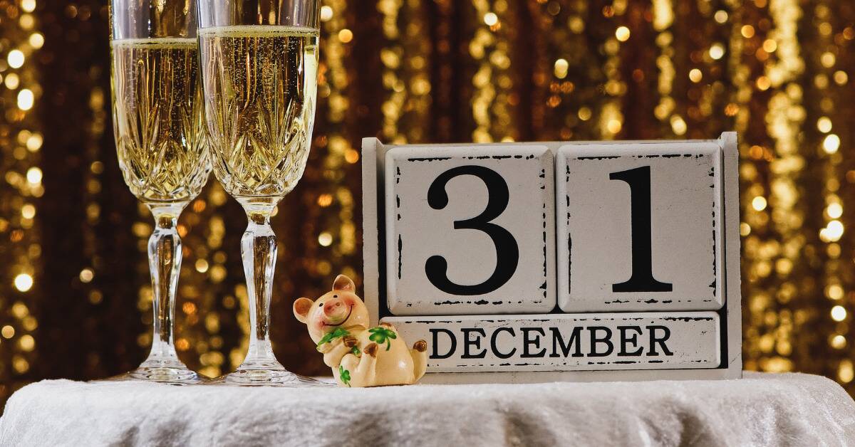 A daily calendar that says '31 December' on a table next to two glasses of champagne.