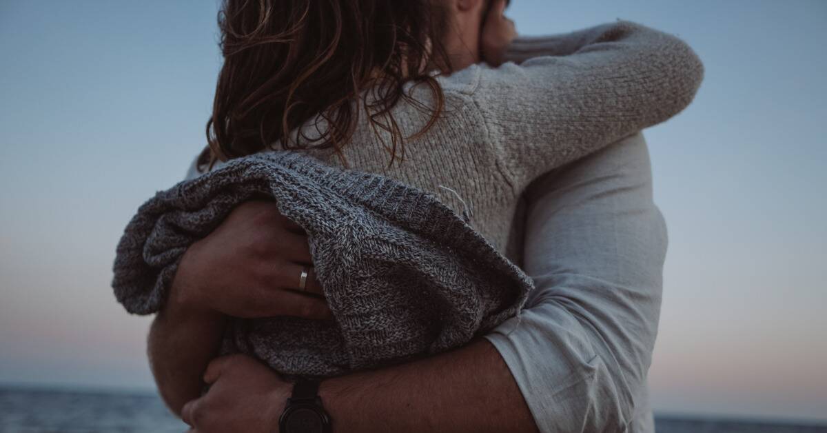 A couple embracing closely at dusk.