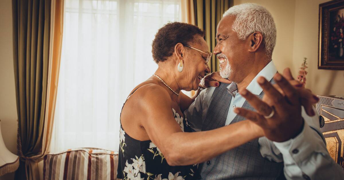 An older couple dancing in their living room.