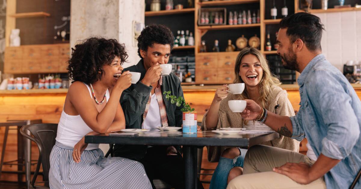 A group of friends chatting and laughing over coffee.
