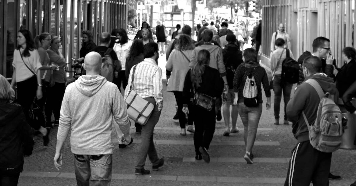 A greyscale image of a crowd walking down a coridor.