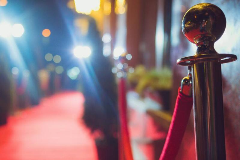 A red carpet with red velvet dividers, the focus on one of the golden divider posts.
