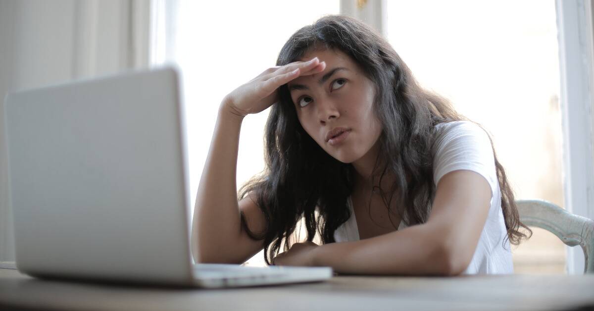 A woman looking annoyed as she sits at her computer.
