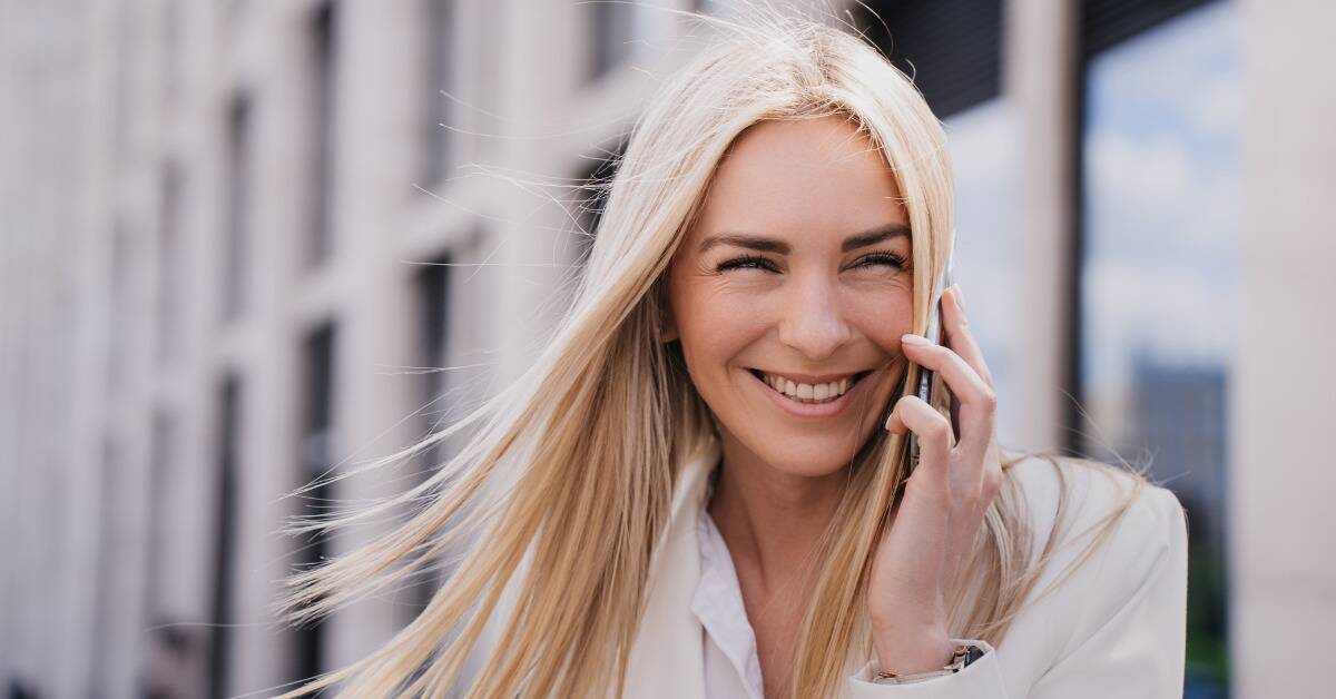 A woman smiling as she talks on the phone.