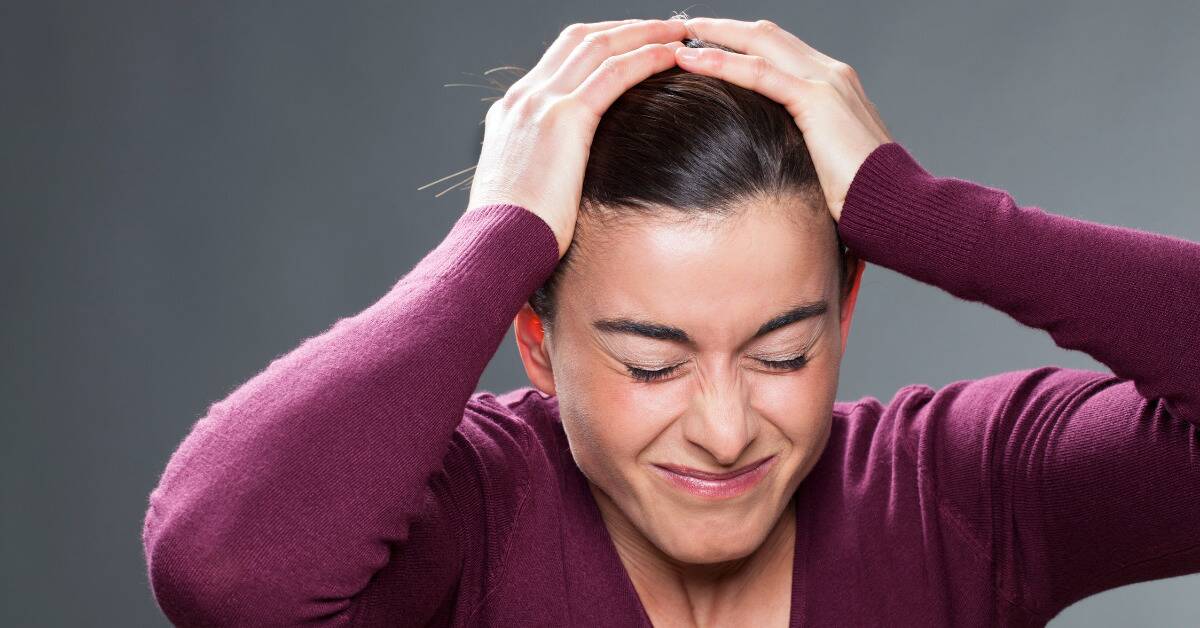 A woman grabbing her head in stress.