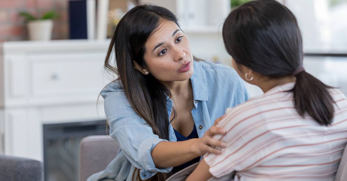 A mother with her hand on her daughter's bicep, looking judgemental.