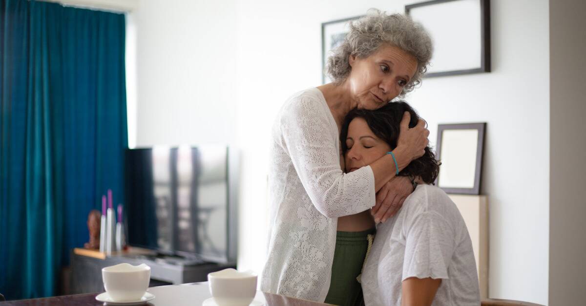 A mother holding her daughter's head to her chest.