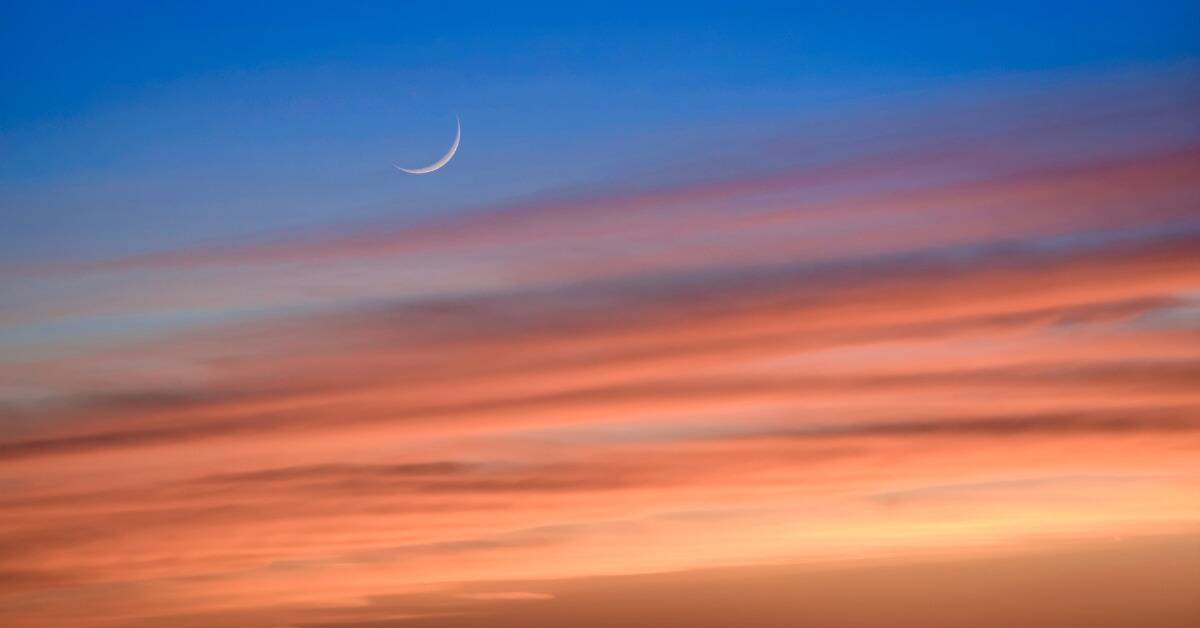 A sunset sky with a light crescent moon visible.