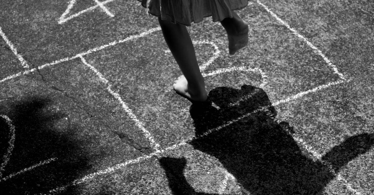 A greyscale image of a child playing hopscotch.
