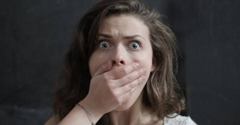 A woman covering her mouth in a scared gasp.