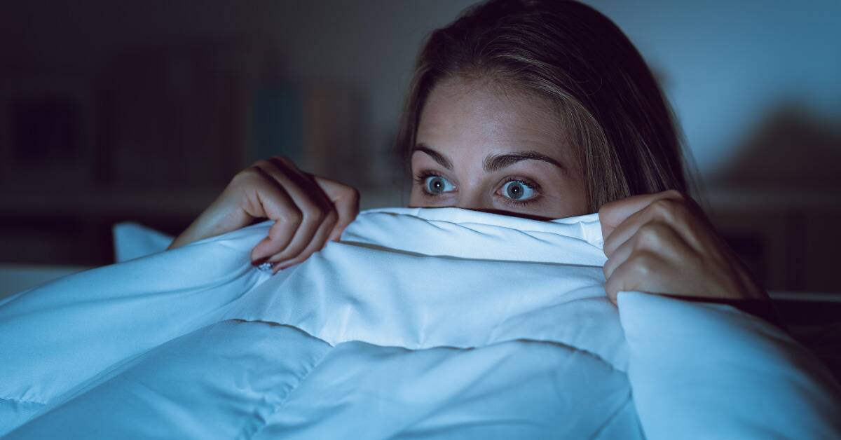 A woman with a blanket pulled up to her eyes.