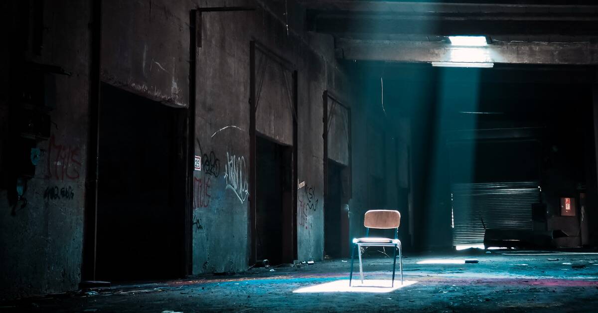 An abandoned school hallway, a skylight shining directly on a chair in the center.