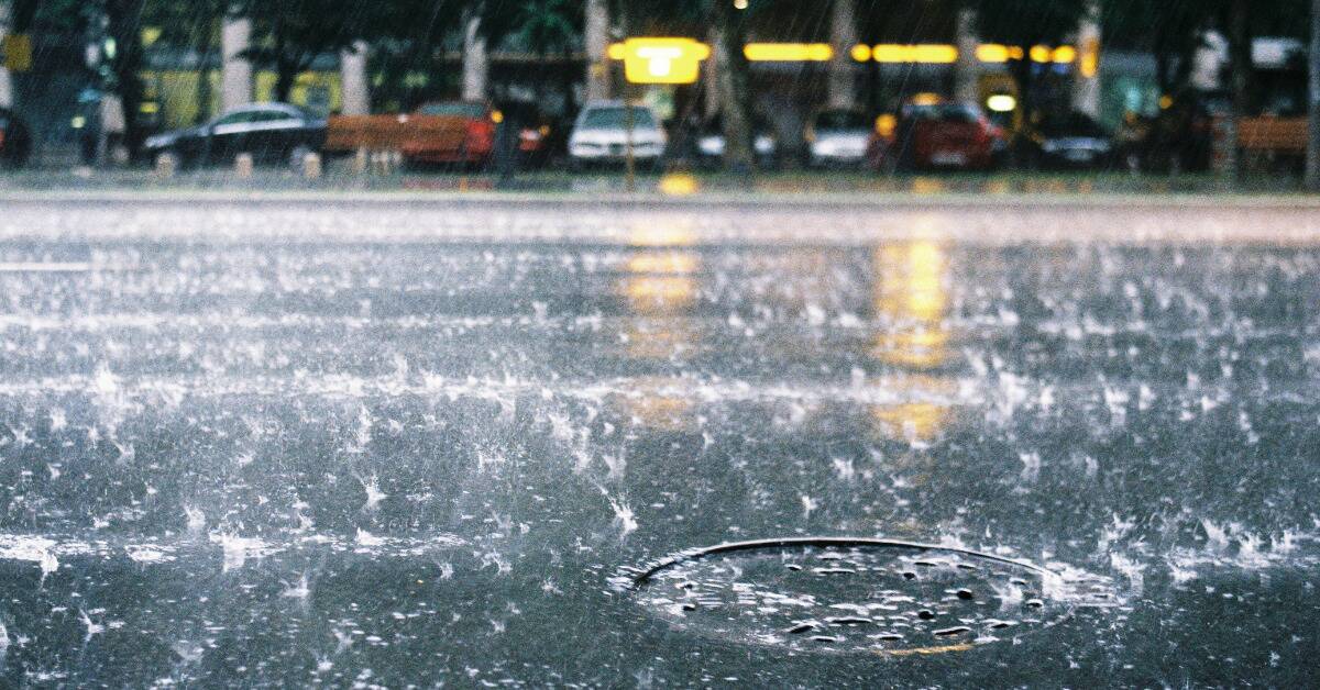 A city street being rained on, the droplets visible as they splash.