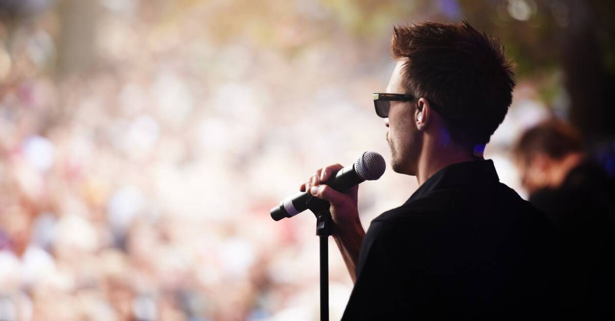 A man in front of a microphone before a large crowd.