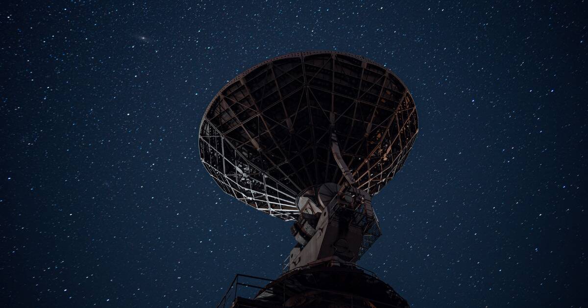 A large satellite pointed at a blue starry sky.