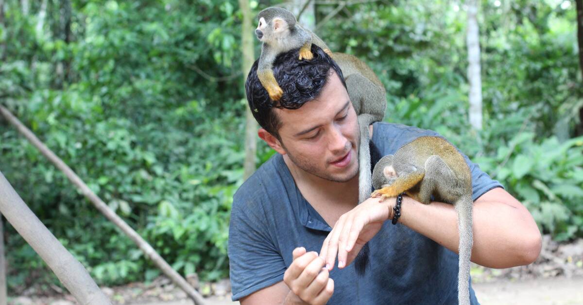 A man with a few small monkeys hanging out on him.