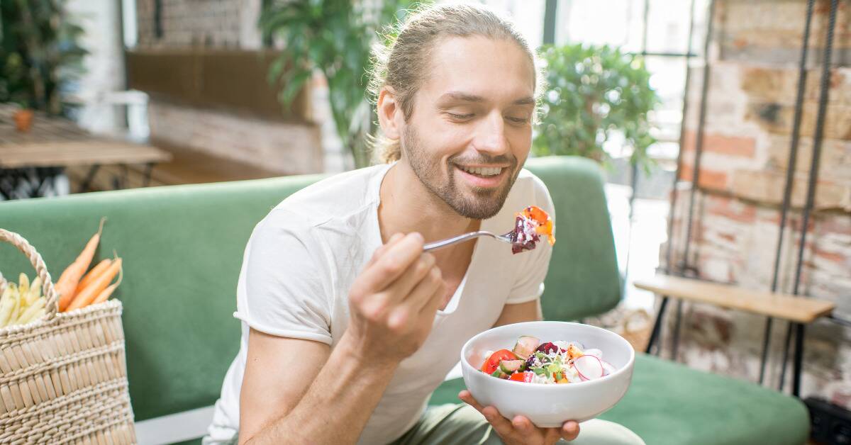 A man sitting on a couch eating a salad.