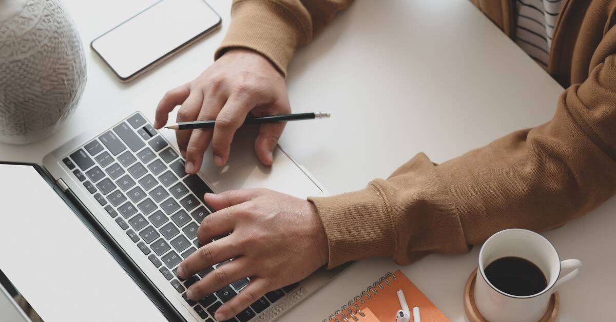 An above shot of someone at their desk typing on their laptop.