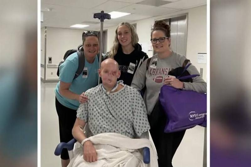 Aaron in the hospital, loved ones around him as he sits in his wheelchair.