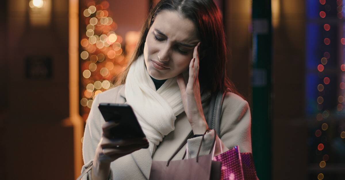 A woman looking worriedly at her phone, seeming stressed.