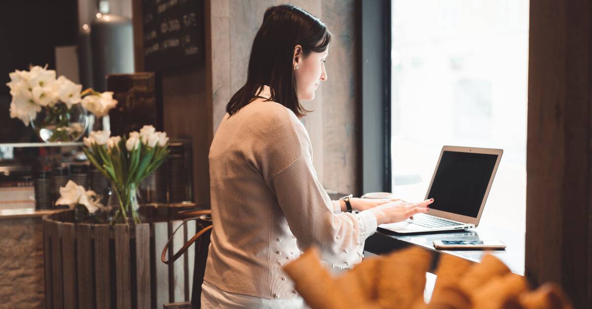 A woman working at her laptop in a cafe.