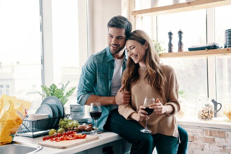 couple smiling having intimate moment in kitchen while cooking