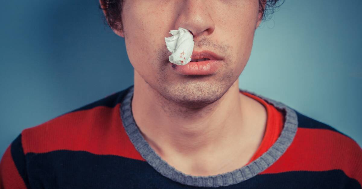 A man with a tissue half-stuck up one nostril.