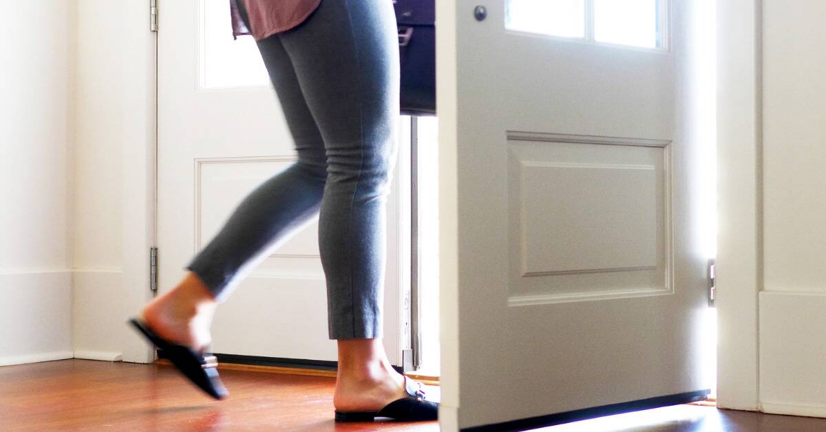 A shot of a woman's legs as she leaves through the front door of a home.