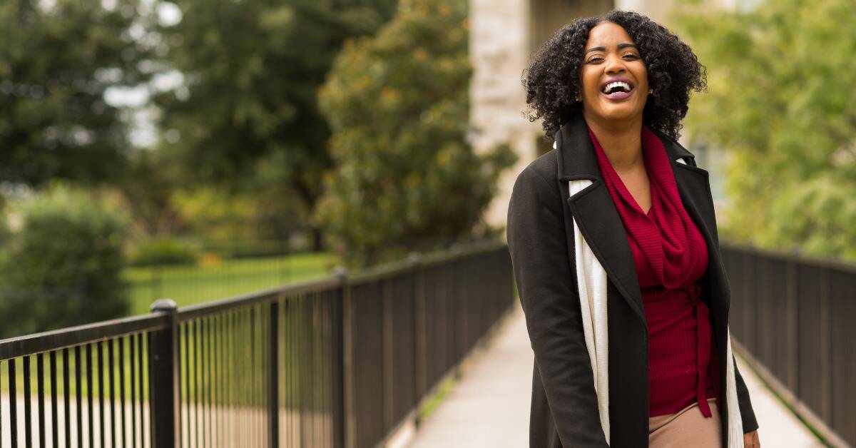 A woman smiling as she stands outside.