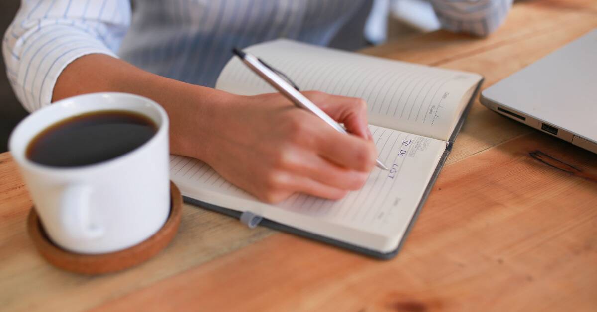 Someone writing out their to-do list in a journal. 