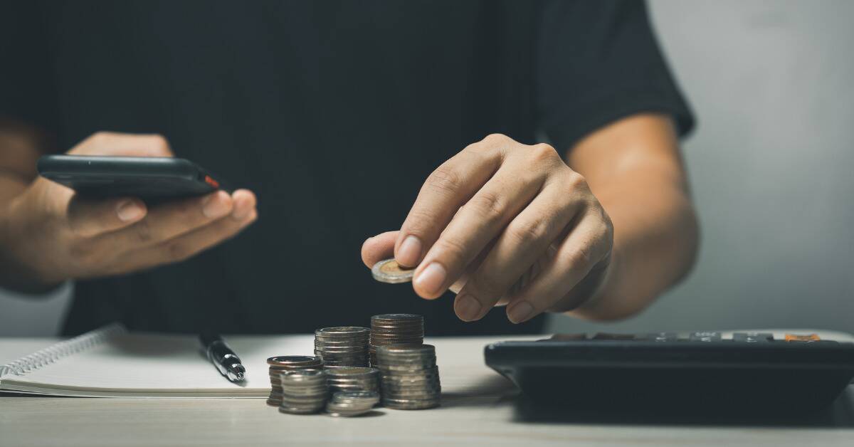 Someone counting out stacks of coins next to a calculator.