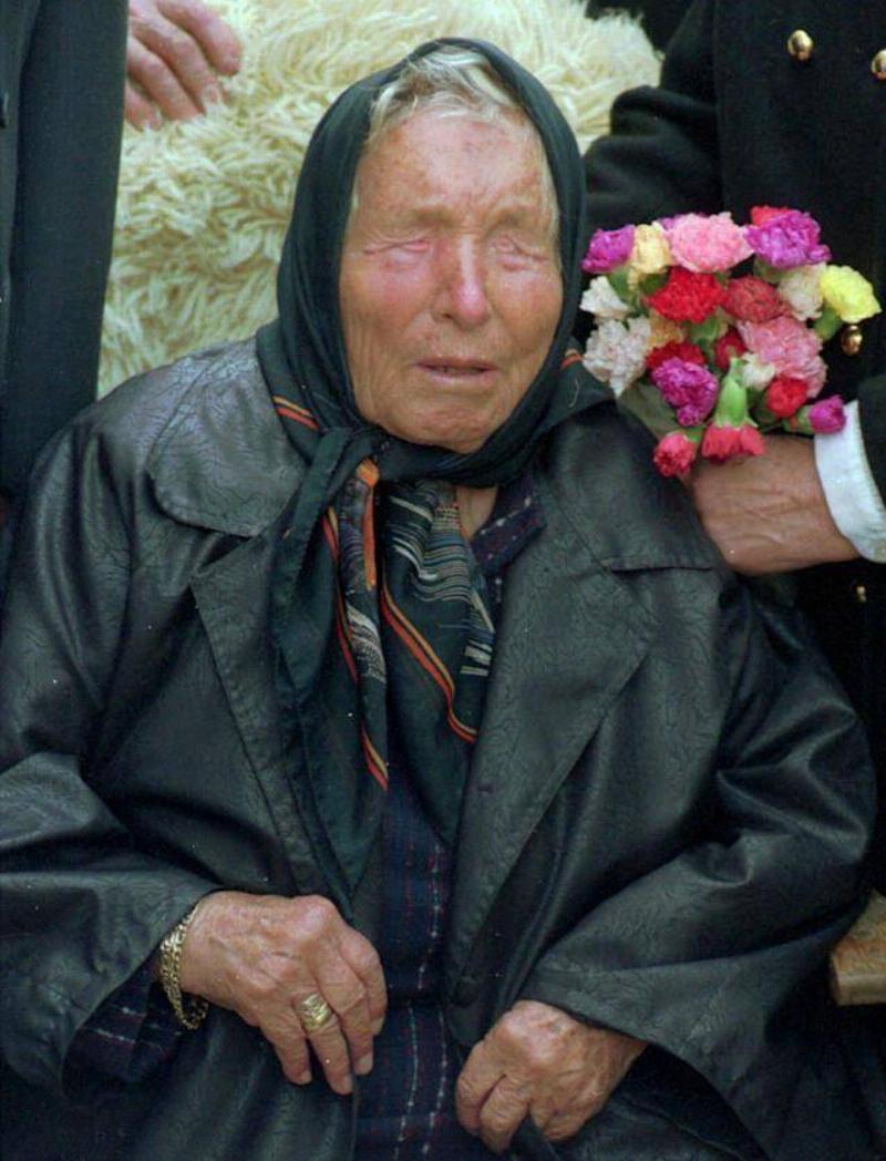 Baba Vanga sitting next to someone who's holding a bouquet of flowers next to her head.