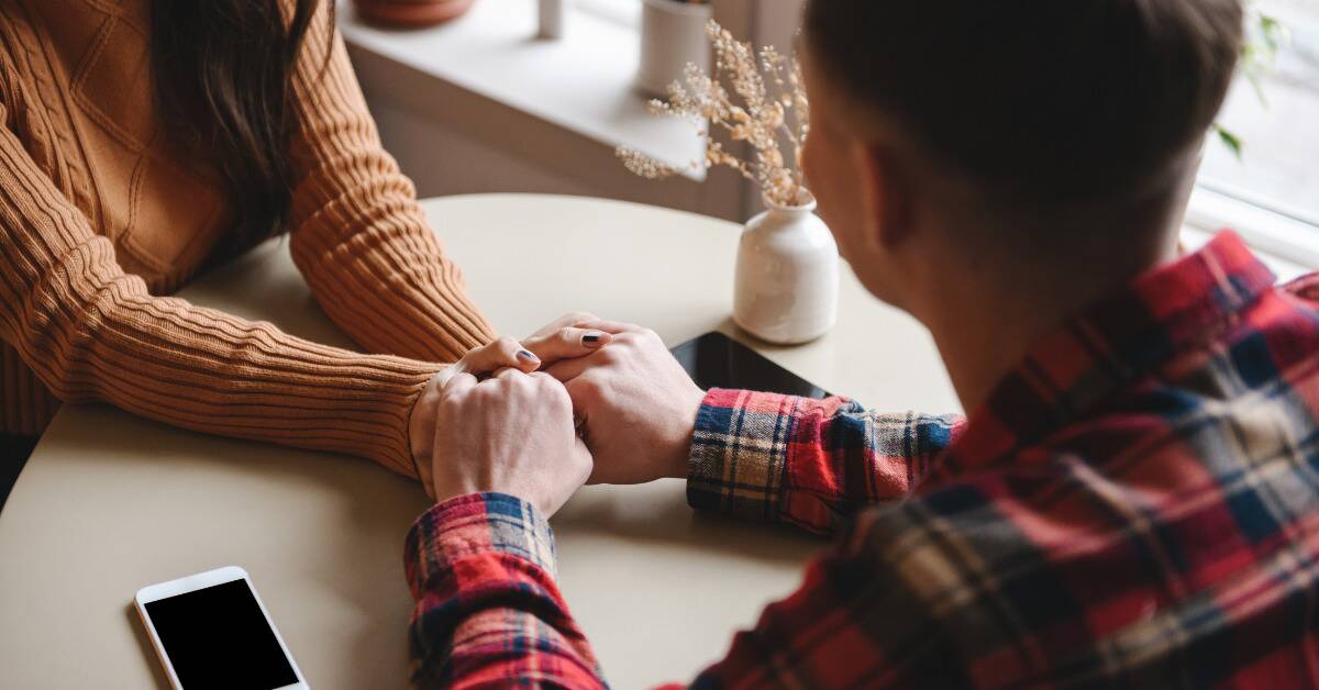 A couple holding hands across a table.