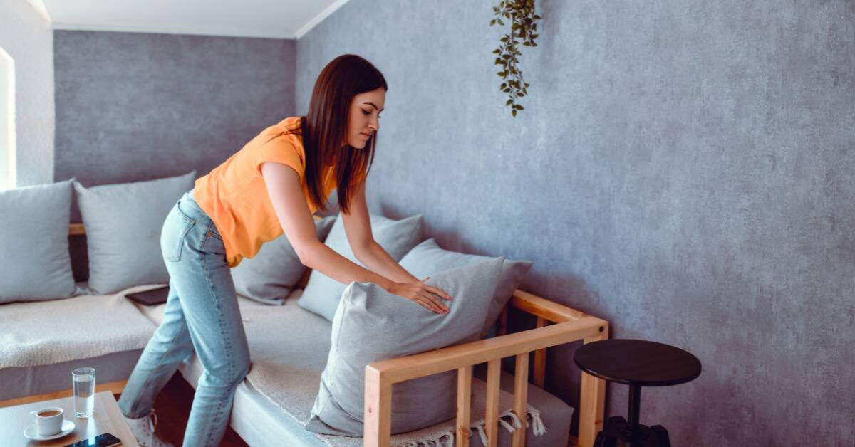 A woman fluffing the pillows on her couch.