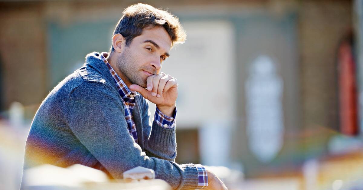 A man sitting with his hand to his chin, looking introspective.