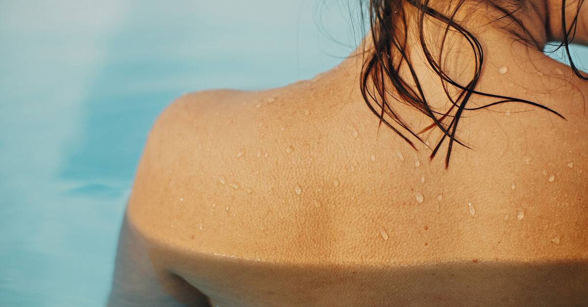 Someone in a pool, their bare shoulders and along their back covered in goosebumps.